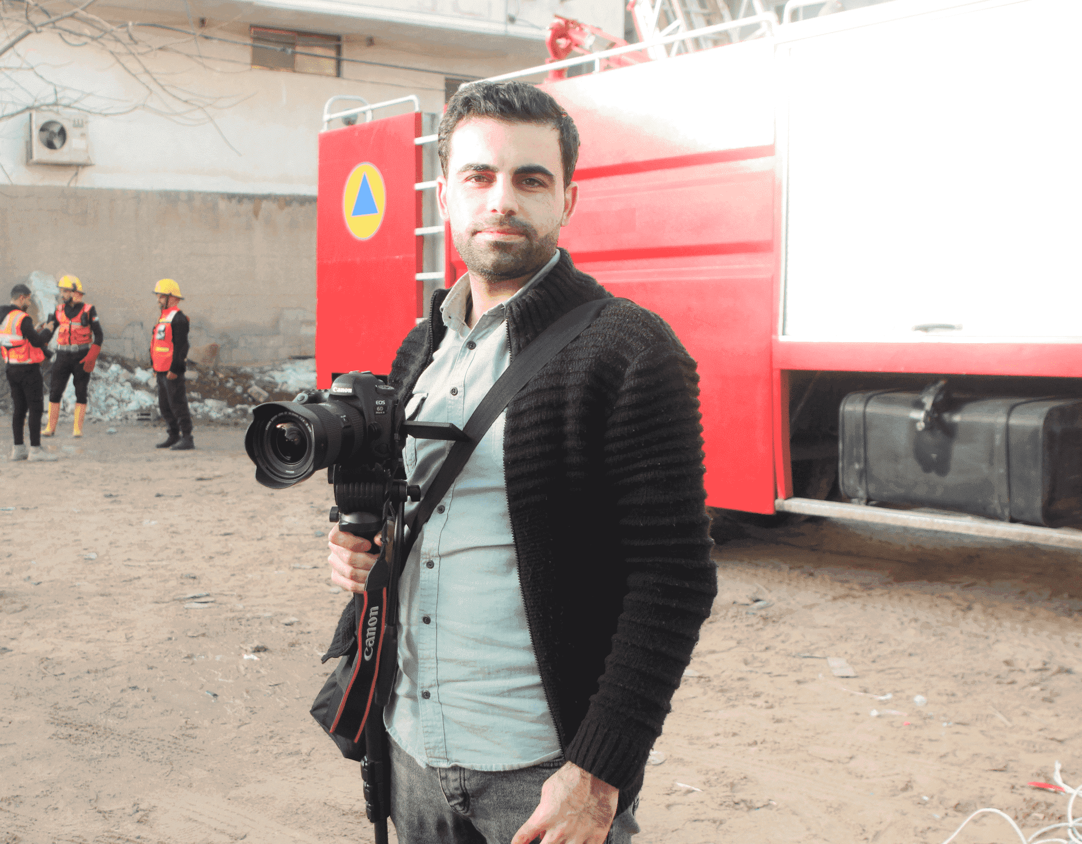 A man stands in front of a trailer with a Canon camera in hand.