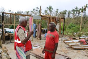 Two people converse in front of debris from a cyclone