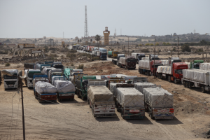 Transport trucks with humanitarian aid lined up near the Egypt-Gaza border, waiting to cross.