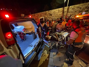 Paramedics putting injured man into an ambulance, surrounded by crowd