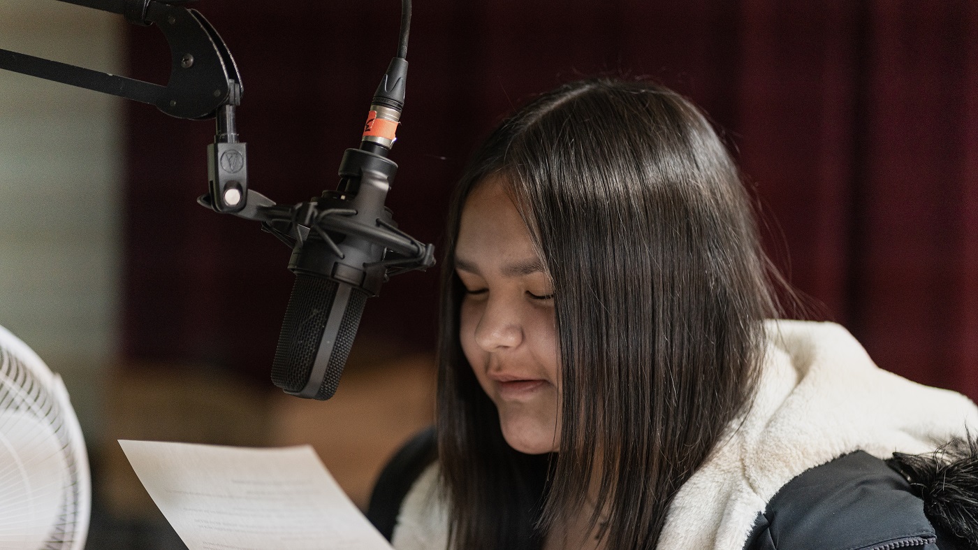 Une jeune femme lit un texte dans un micro.