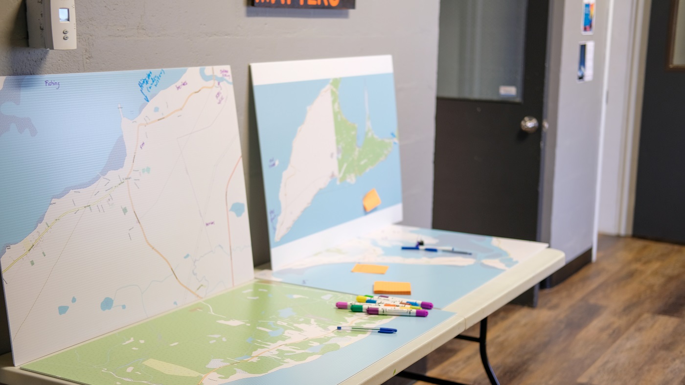 Four maps are displayed on a table with markers to write on the maps