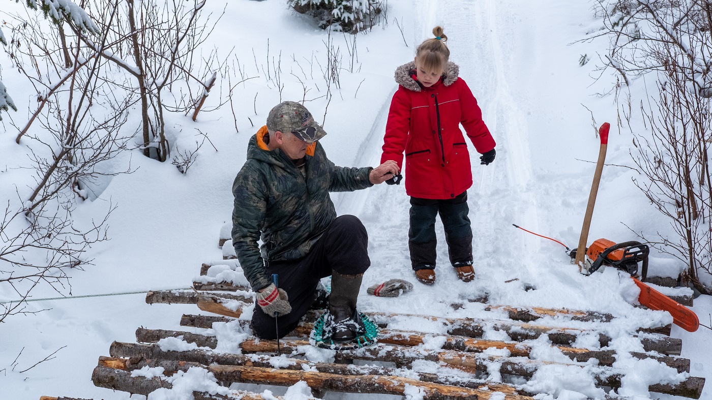 Un homme et sa fille ramassent du bois à l'extérieur pendant l'hiver afin de se préparer aux urgences.