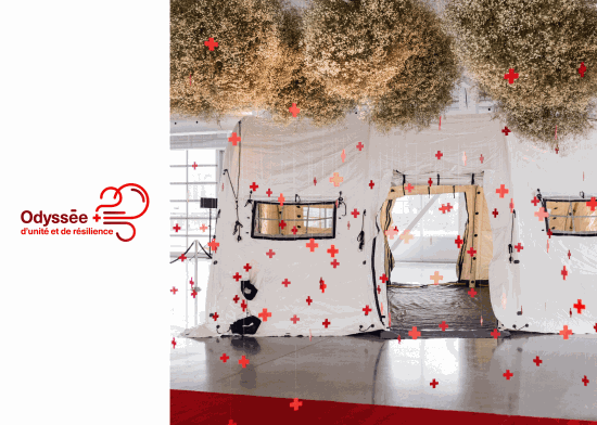 A white tent with Canadian Red Cross logo and flower arrangement on the ceiling.